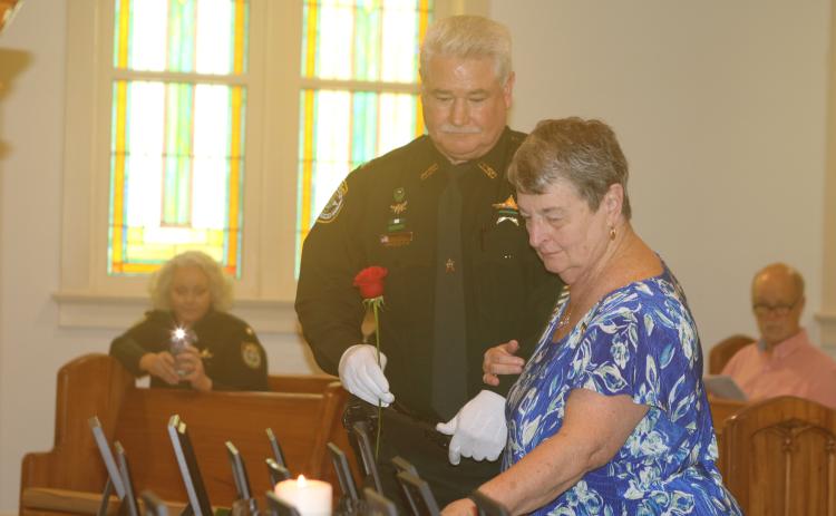 Pat Davis places a rose to honor her son, late Columbia County Sheriff’s Deputy Jeff Davis, during last year’s Public Safety Memorial ceremony. (FILE)