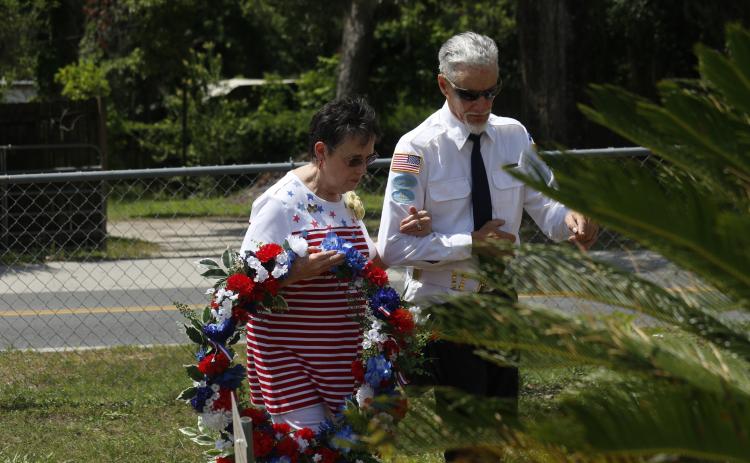 Rosemary Ivie with the Live Oak Garden Club prepares to place a wreath at the veterans memorial during the Memorial Day observance Monday at the Live Oak Cemetery. (JAMIE WACHTER/Lake City Reporter)