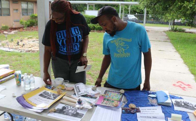 Shanetha Anthony (from left) and Damarrick Hendon, look through Eastside Elementary School items that were pulled from a time capsule to the school’s final walkthrough on Thursday afternoon. (TONY BRITT/Lake City Reporter)