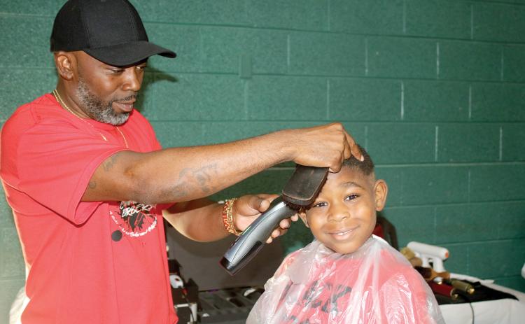 Tyrone Mullins, giving a haircut at a previous Community Barbers Back to School Bash, said this is a special year for the event as it marks its 10th anniversary. (FILE)