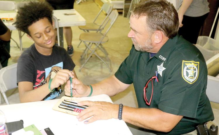 Darren Simmons (left), 13, gives his opinion to School Resource Deputy Scott ‘Chewy’ Ceckanowicz on his picture frame. (TONY BRITT/Lake City Reporter)