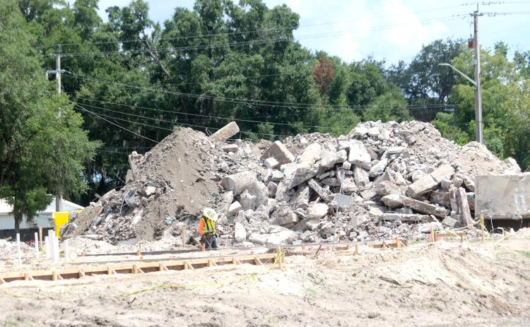 A construction worker looks at some concrete slabs that have been poured on the Eastside Elementary School campus Wednesday as a mountain of debris from the previous school is piled up behind him. (TONY BRITT/Lake City Reporter)