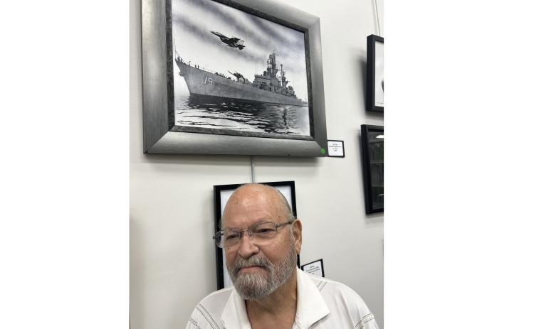 Benjamin Ragland poses in front of his winning drawing of the USS Dale with an F14 Tomcat flying overhead.