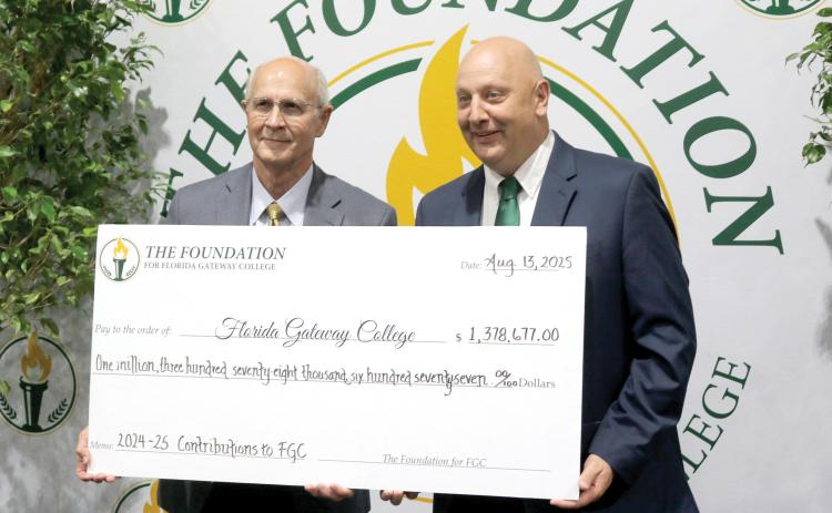 Van Long (left), the Foundation For Florida Gateway College board chair, stands with Lawrence Barrett, Florida Gateway College President, holding a ceremonial check for $1.3 million, representing funds for scholarships and to support other programs at the college. (TONY BRITT/Lake City Reporter)