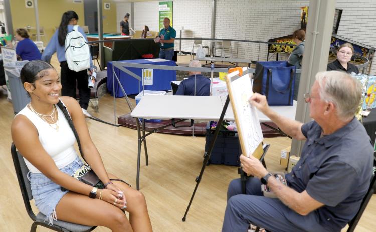 Angelina Jenkins (left) smiles as Dino Casterline draws her caricature during Florida Gateway College’s Welcome Week 2025 Festivities on Monday afternoon. (TONY BRITT/Lake City Reporter)
