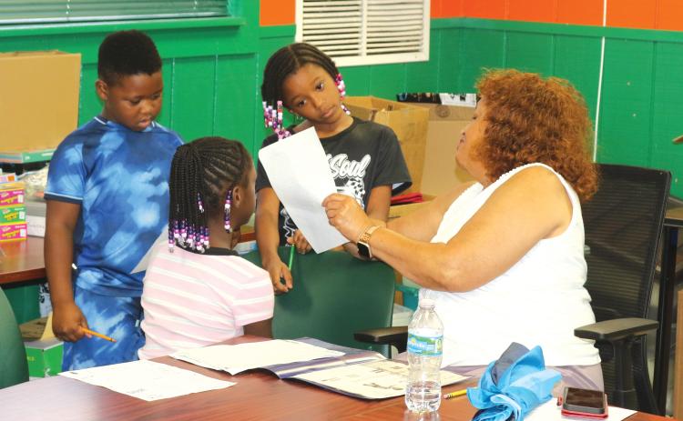 Narrie Smith, a retired Columbia County School District educator, helps children with their homework while they are at the NorthStar Family Resource Center on Tuesday afternoon. (TONY BRITT/Lake City Reporter)