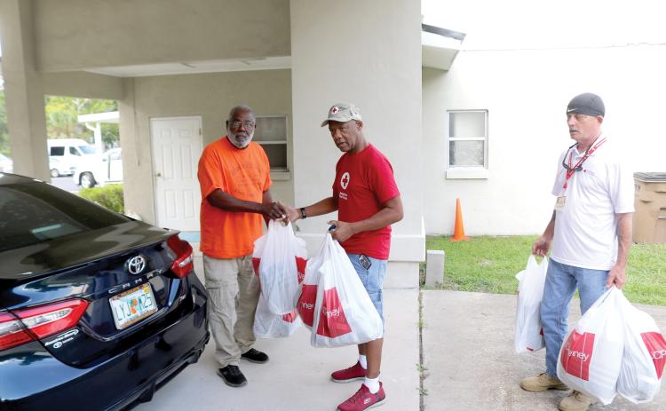 Bernard George (from left), brings bags of donations for displaced fire victims to American Red Cross workers Darryl Crawford and Doug Silvey on Thursday afternoon. (TONY BRITT/Lake City Reporter)