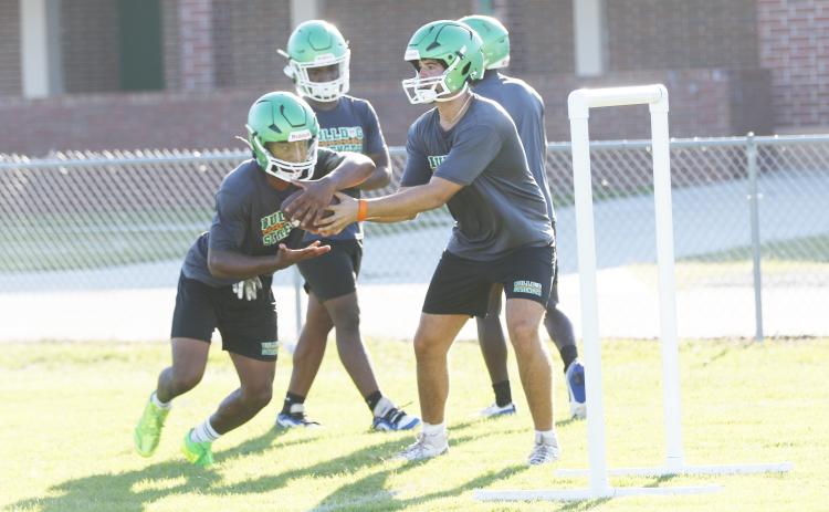 Suwannee quarterback Thomas Sikes (right) hands the ball off to running back Lou Jack Smith during Monday’s practice. (JAMIE WACHTER/Lake City Reporter)