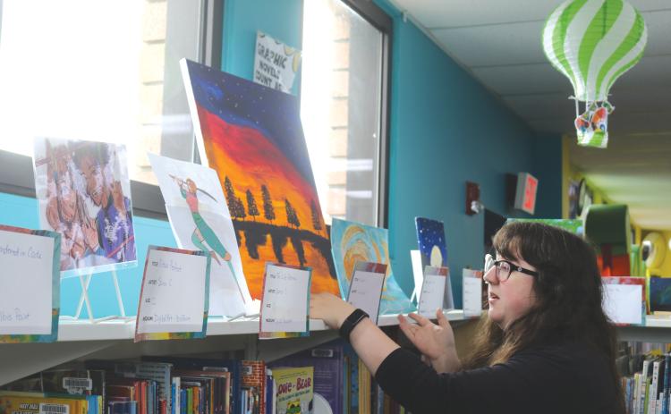 Columbia County Public Library Programming Specialist Emma Chieuw arranges art pieces ahead of the library's 2025 Youth Art Contest. (TONY BRITT/Lake City Reporter)
