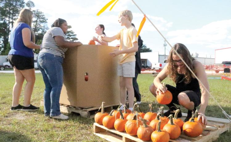 Ryan Pursel arranges pumpkins on a pallet at the Columbia High School Pumpkin Patch. Local FFA students are trying to sell the 1,502 pumpkins as a fundraiser. (TONY BRITT/Lake City Reporter)