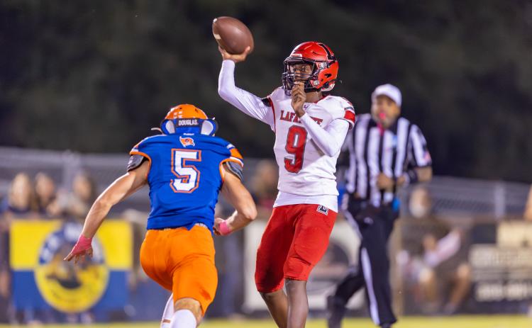 Lafayette quarterback Tywan Williamson releases a pass as Branford’s Devin Waller closes in Friday. (JACK HOWDESHELL/Lake City Reporter)