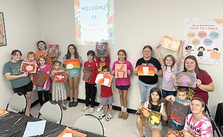 Participants in the first ‘Messy Masterpieces’ class at the West Branch Library show off their artwork Saturday. (COURTESY)