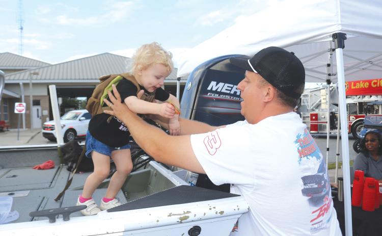 Landry Levai (from left), 2, gets a lift from Blaise Levai after walking on the Columbia County Sheriff’s Office Search and Rescue Boat during the National Night Out event on Tuesday evening. (TONY BRITT/Lake City Reporter)