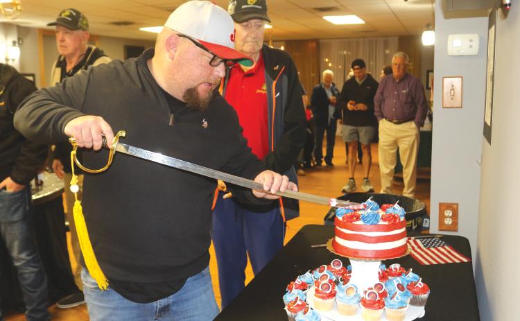 Kyle Warner, keynote speaker for the Lake City Elks Lodge #893 Marine Corps 250 birthday celebration, uses a sword to cut the birthday cake for the event. (TONY BRITT/Lake City Reporter)
