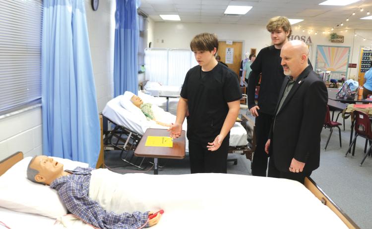 Fort White High School Health Occupation Science Academy students Jack Schroader (from left) and Christopher Meagher explain how they conduct a patient examination to FEA President Andrew Spar, who visited the school on a tour Tuesday afternoon. (TONY BRITT/Lake City Reporter)
