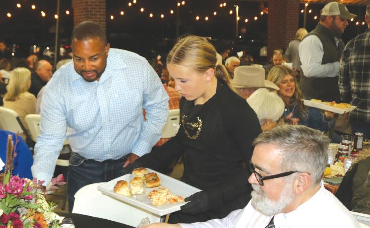 Weslyn Feagle (center) provides lasagna and garlic knots for Columbia County Commissioner Kevin Parnell (left) and County Manager David Kraus during Thursday night’s Farm to Table event at Darby Pavilion. (TONY BRITT/Lake City Reporter)