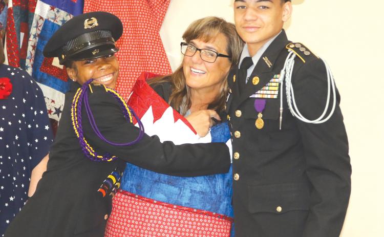First Sgt. Trena Dettmer, Columbia High School JROTC instructor, is hugged by students after she received a Quilt of Valor from the Lady of the Lake Quilters Guild on Wednesday morning. (TONY BRITT/Lake City Reporter)