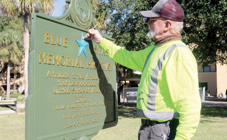 Thomas L. Stelling with Historical Markers Restorations paints the blue star on the Blue Star Memorial Highway marker that sits in front of the Lake City VA Hospital. Stelling restored the sign last week for the Lake City Garden Club. (TONY BRITT/Lake City Reporter)