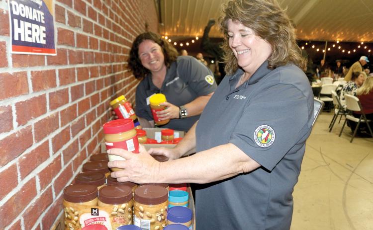 Paulette Tomlinson (right) and Heather Futch with the Columbia County UF/IFAS Extension Office sort through jars of unopened peanut butter that were donated for the 2025 Peanut Butter Challenge at the Farm to Table event earlier this month. (TONY BRITT/Lake City Reporter)