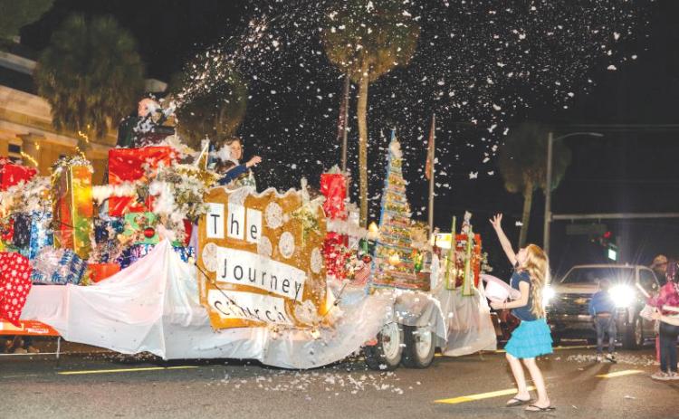 A girl tries to catch ‘snow’ blowing off The Journey Church’s float during a prior Downtown Christmas parade in Mayo. (FILE)
