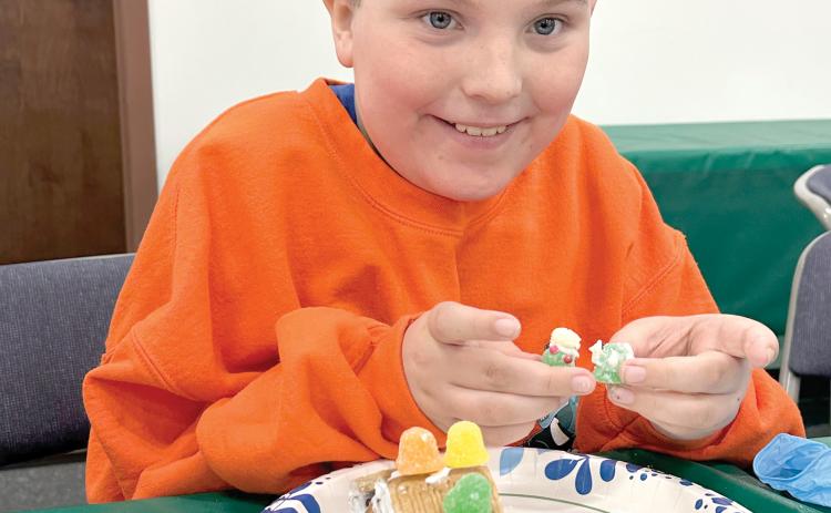 Donovan Corbett shows off some additions to his gingerbread house as he continued to work Monday during the 4-H STEM Explorers Club’s Christmas meeting. (COURTESY)