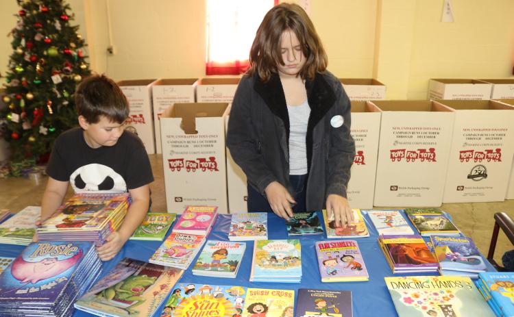 Phury Hunlock (left), 10, and Piper Hunlock, 13, volunteer their time arranging books that will be given as Toys for Tots Christmas gifts. (TONY BRITT/Lake City Reporter)
