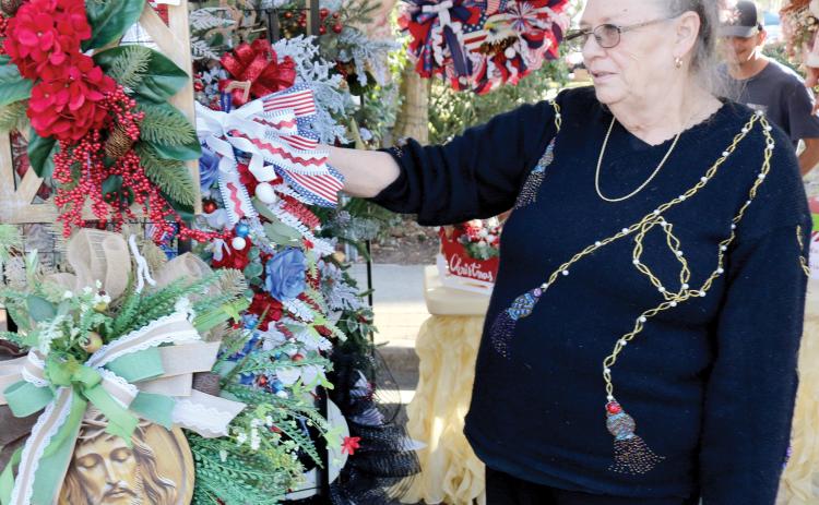 Deborah Water of Fort White, a vendor in the local holiday market, organizes Christmas wreaths in her booth. (TONY BRITT/Lake City Reporter)