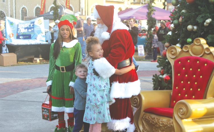 A child hugs Santa Claus at last year’s Light Up the Night Christmas Tree Celebration in Olustee Park. (FILE)