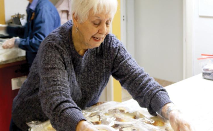 Anne Tatem covers desserts that were provided with dinner during food preparation for the cold weather shelter at Parkview Baptist Church. (TONY BRITT/Lake City Reporter)
