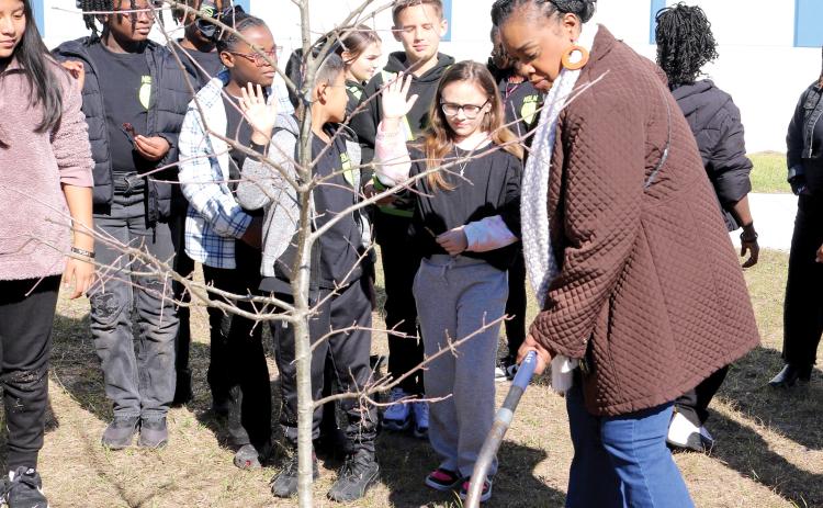 Niblack Elementary School Principal Makeba Murphy adds dirt to the hole where a Shumard Oak tree was planted at the school on Friday for Florida Arbor Day. The tree was donated by the Lake City Garden Club. (TONY BRITT/Lake City Reporter)