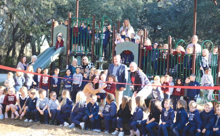 Students and staff at Belmont Academy pose for a ribbon-cutting ceremony during Monday’s debut of their new playground equipment. (TONY BRITT/Lake City Reporter)