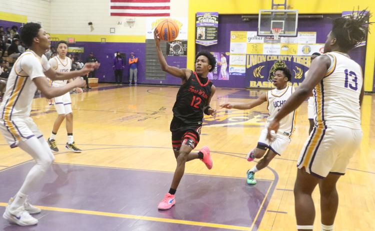Fort White's Jonathan Bessent drives through the lane against Union County center Adrian Manns (left) and forward Tyrese Chandler during Thursday's District 6-R semifinal. (MORGAN MCMULLEN/Lake City Reporter)