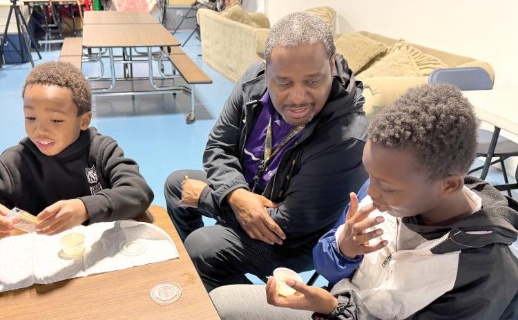 Niblack Elementary physical education coach James Williamson coaxes students Augest and Kingston to try the results of their efforts in making butter. (COURTESY UF/IFAS EXTENSION COLUMBIA COUNTY)