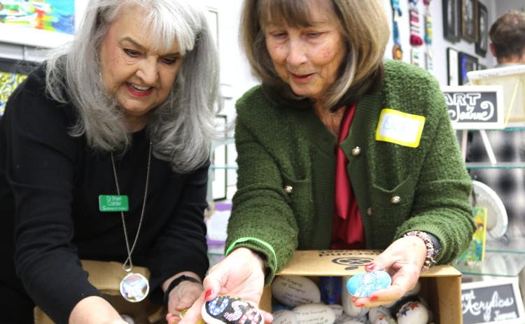 Sheri Carder (left) and Dee Etheridge have fun and share laughs while they go through a box of Freedom Rocks at the Gateway Art Gallery last month. (TONY BRITT/Lake City Reporter)