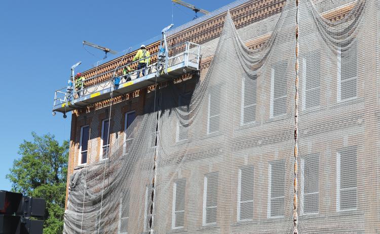 Innovative Masonry Restoration workers get set on tearing down the netting surrounding Lake City Hall. The netting will not make a return once it’s down. (TONY BRITT/Lake City Reporter)
