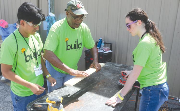 Angel Gomez, a Columbia High School student, gets tips on sanding wood from Monty Ashby, as Gomez and Kiley Morrison sand wood to make beds for the Sleep in Heavenly Peace program during last year’s Build My Future event. (FILE)