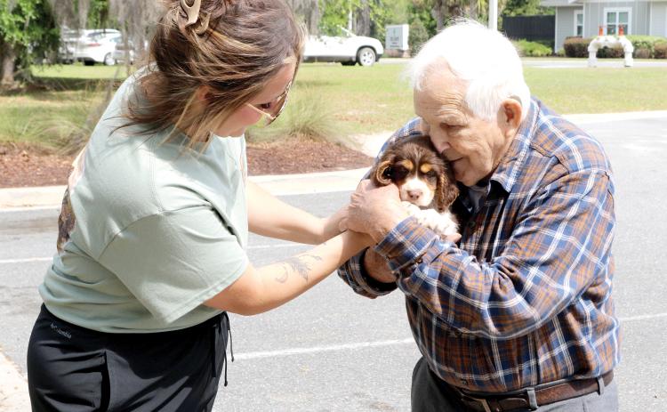 Stephanie Spradley with Spradley Springers passes a puppy to Donald Altman to love on during activities at the Easter Extravaganza at the Canopy at Harper Lake on Saturday. (TONY BRITT/Lake City Reporter)