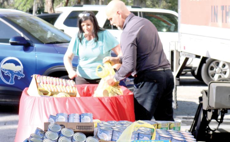 April Powell (left) and Todd Denmark, Circle of Life Assisted Living Facilities employees, unload bags of food stable items that were donated to Catholic Charities during the March Against Hunger event on Thursday afternoon. Circle of Life Assisted Living facilities contributed 1,126 canned goods to the food collection drive. (TONY BRITT/Lake City Reporter)