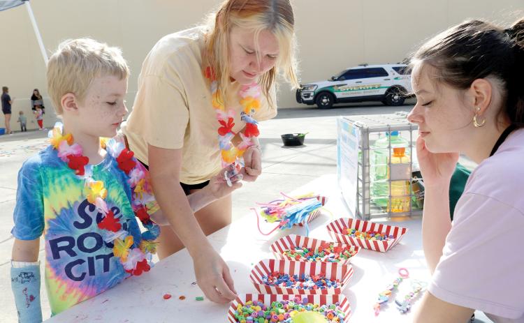Ryan Poirier (clockwise from left), 6 and Callie Poirier make a bubble wand with help from Bella Heser during the MESS-tival event at the West Branch Library on Thursday morning. (TONY BRITT/Lake City Reporter)