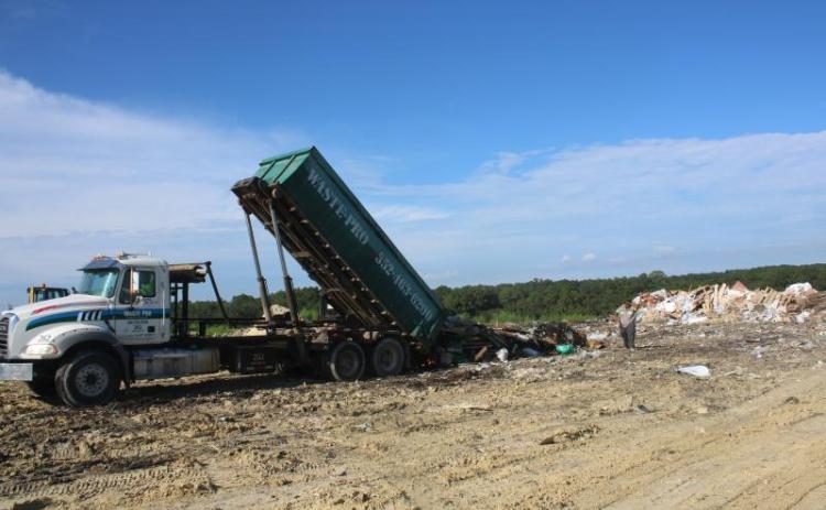 A pair of Waste Pro employees oversee the dumping of a truckload of garbage at the Columbia County Landfill. (FILE)