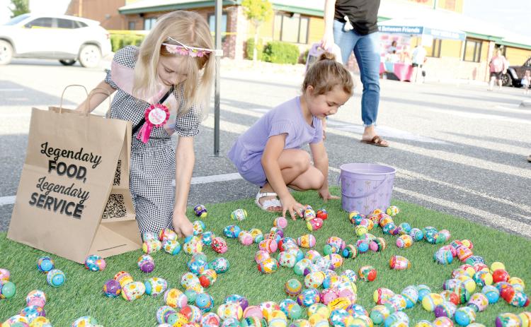 Riley Poirier (left), 8, and Kingsley Burnham, 4, look through Easter eggs at the Movement Mortgage Tent on Tuesday evening at the Texas Roadhouse Second Annual Easter Egg Hop event. (TONY BRITT/Lake City Reporter)
