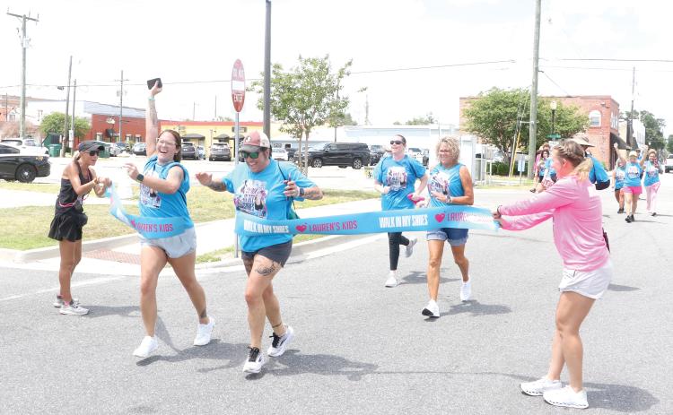 Local walkers cross the finish line in downtown Lake City on Tuesday morning after completing the eight-mile Lauren’s Kids Walk in My Shoes event. It’s the first time the statewide walk has made a stop in Lake City. (MORGAN MCMULLEN/Lake City Reporter)