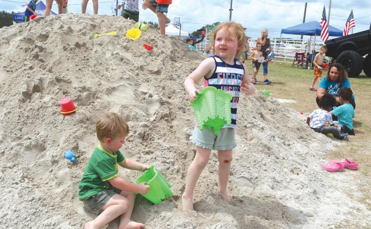 Benton Graham (left) and Lundee Graham play in a pile of sand during last year’s Kiwanis Kids Day. (FILE)