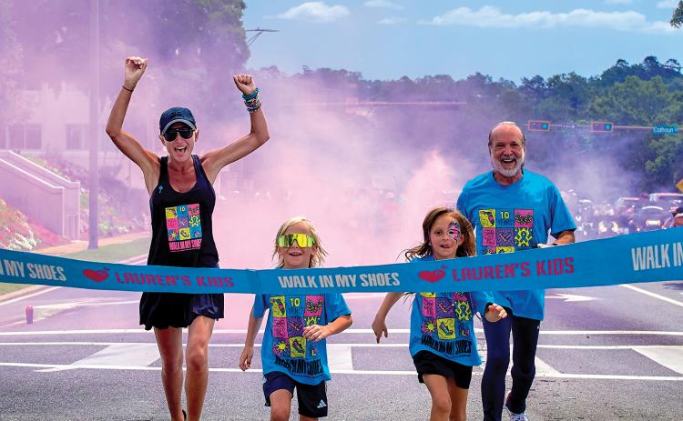 Lauren Book, a survivor and the founder of Lauren’s Kids, completes a walk at one of the stops during last year’s Lauren’s Kids Walk, along with a pair of children and her father, Ron. (COURTESY)