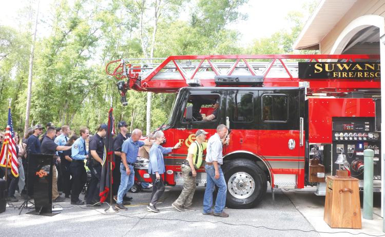 Suwannee County Commissioner Travis Land leads a group of county residents and firefighters in pushing the new ladder truck into the Dowling Park station Wednesday morning. (MORGAN MCMULLEN/Lake City Reporter)