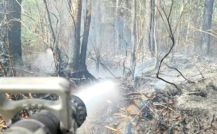 Firefighters utilize water to help extinguish heat within the root system of trees and the duff layer on the Sargent fire in order to reduce risk of rekindle and help fully contain the fire. The wildfire, which began in Baker County on Thursday and has spread to northeastern Columbia County is 50% contained. (COURTESY FLORIDA FOREST SERVICE)