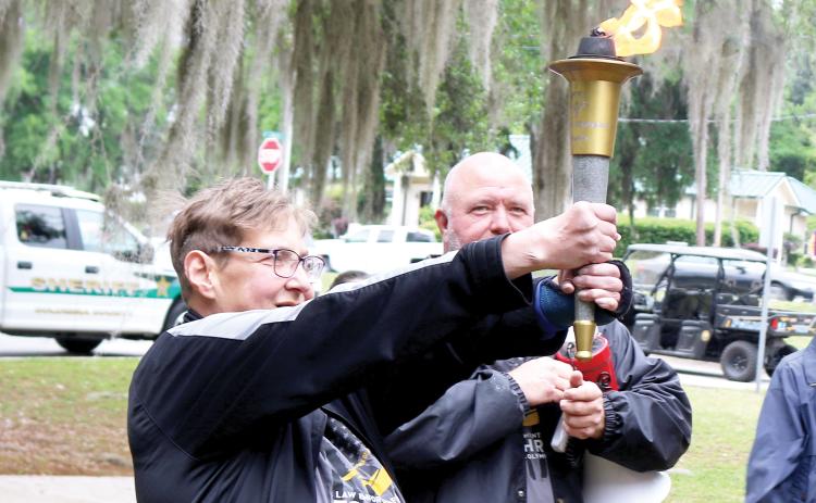 Carly Dolly, a Special Olympics athlete leader in Columbia County, served as this year’s torch bearer during Tuesday’s Special Olympics Law Enforcement Torch Run and was given the torch as it was lit by Columbia County Sheriff’s Office Sgt. Clint Dicks. (TONY BRITT/Lake City Reporter)