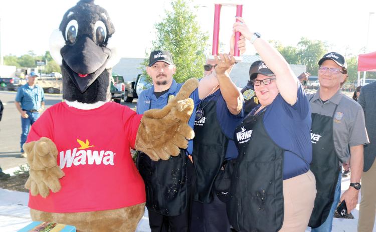 Wally the Goose presents representatives from the Lake City Police Department with a trophy after they defeated the Lake City Fire Department team in a hoagie-making challenge. (TONY BRITT/Lake City Reporter)