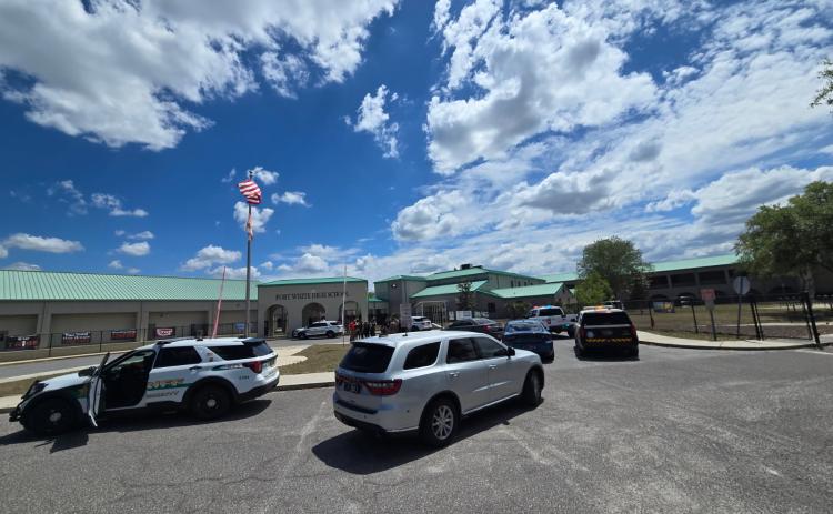 A law enforcement presence gathers near the front entrance to Fort White High School on Wednesday afternoon. The move followed an anonymous phone call to the school district that threatened student safety. (COURTESY)