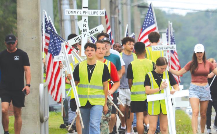 Columbia High School JROTC cadets carry flags and crosses that will be placed alongside State Road 47 in honor of veterans and first responders. (TONY BRITT/Lake City Reporter)